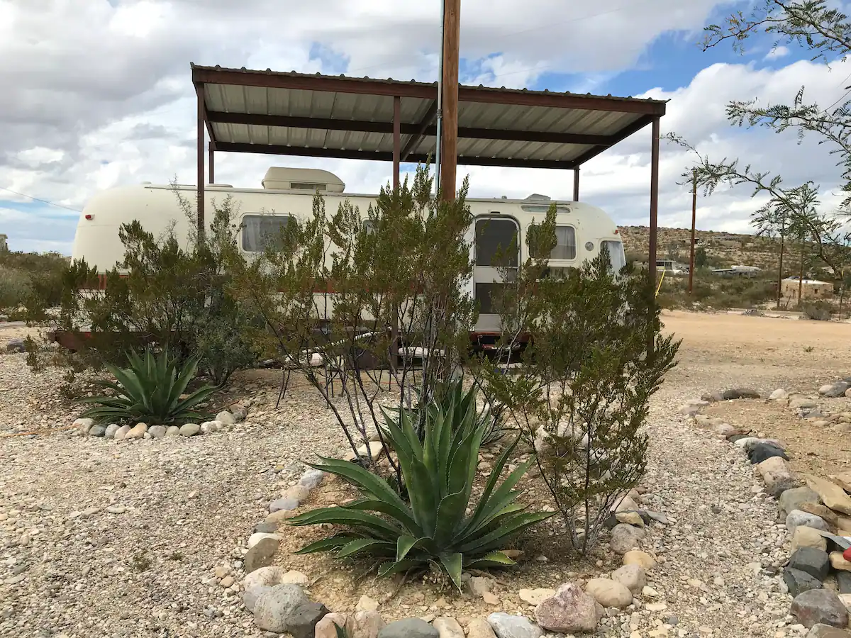 5a95a99f-2673-4f06-bf7d-46f57cd86b2d A desert scene with an rv and plants.